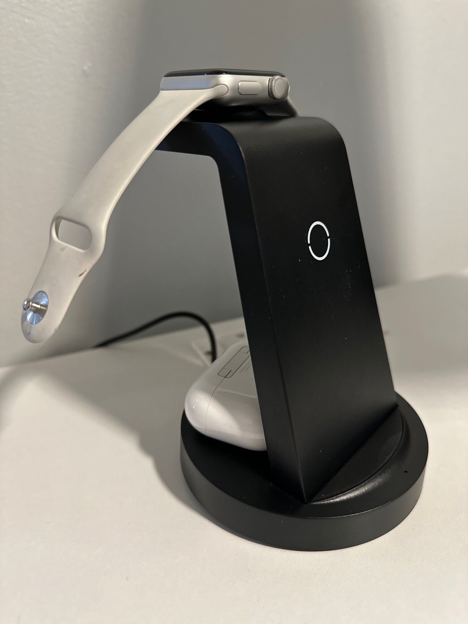 A charging station with a sleek design, featuring a curved arm and a circular button on the side.
