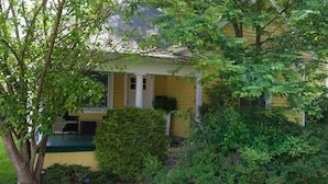 A yellow house with a porch, surrounded by greenery. - Cozy-Hoosier themed bungalow-Walk to best city parks and Downtown. (Bloomington)