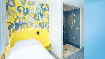Una habitación de hotel con cama, ducha y una pared decorada con arte abstracto.
