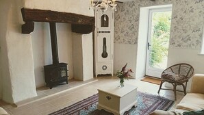 A cozy living room with a fireplace, a white chest of drawers, a wicker chair, and a patterned rug.