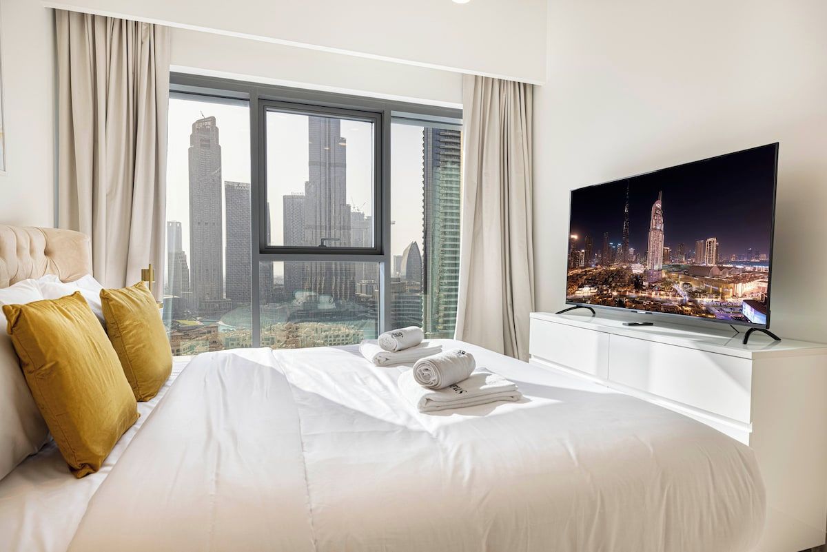 Ein Hotelzimmer mit einem großen Bett, einem Fernseher und Blick auf die Stadt.