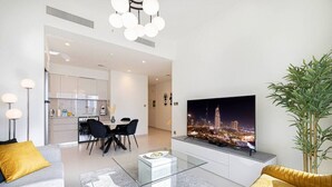 A modern living room with a flat-screen TV, a dining area, and a kitchen. - New 2B | Burj Khalifa | Dubai Mall | 2 Pools | Gym (Dubai)