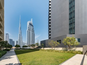 A modern building with a flat roof, large windows, and a paved courtyard with grass and trees.