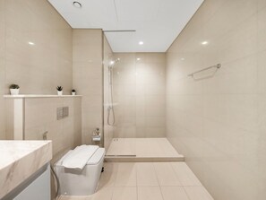 Een moderne badkamer met een douche, toilet en wastafel.