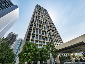 A high-rise building with a grid of windows and balconies, surrounded by greenery and other buildings. - New 2B | Burj Khalifa | Dubai Mall | 2 Pools | Gym (Dubai)