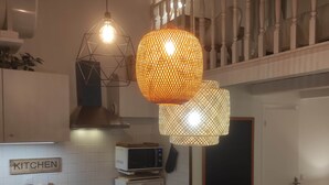 A modern kitchen with white cabinets, a microwave, a stove, and a hanging light fixture. - Chill Out Cabanon Charme Calanques à 30 m de L'eau (Marseille)