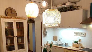 A dining area with a wooden table and chairs, a cabinet with glass doors, and a kitchen area with a sink and stove.