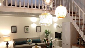 A spacious living area with a dining table, sofa, and staircase.