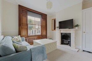 A living room with a sofa, a coffee table, a fireplace, and a television.