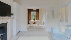 A living room with a fireplace, a TV, a dining area with a table and chairs, and a sofa. - Prime Location 2 Bed East London (London)