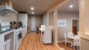 A modern kitchen with white appliances, a dining area with a white table and chairs, and wooden flooring. - Cobb Mountain Chalet King Size Suite (Cobb)