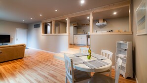 A modern living room with a sofa, a dining table with chairs, and a kitchen in the background. - Cobb Mountain Chalet King Size Suite (Cobb)
