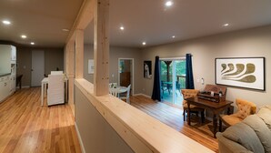 A spacious kitchen with wooden flooring, a dining area with a table and chairs, and a living room with a sofa. - Cobb Mountain Chalet King Size Suite (Cobb)