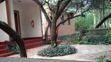 A building with red steps leading to a door, surrounded by trees and plants.