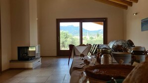 A dining area with a wooden ceiling, a large window with a mountain view, and a table set with various dishes.