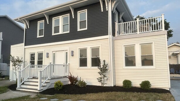 A two-story house with a front porch, a small deck, and a well-maintained lawn. - Luxury Boho Bay House. Balcony with Sunset Views, Near Casinos & Beach (Pleasantville)