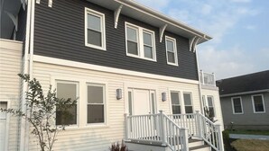 A two-story house with a front porch, white railings, and a small garden area. - Luxury Boho Bay House. Balcony with Sunset Views, Near Casinos & Beach (Pleasantville)