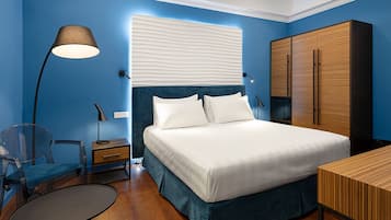 A bedroom with a bed, a desk, a chair, a wardrobe, and a lamp.