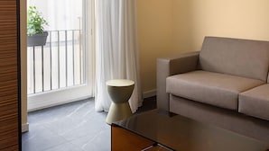 A modern living room with a sofa, a coffee table, and a view of a balcony with a potted plant. - Poerio 25 Boutique Stay (Naples)