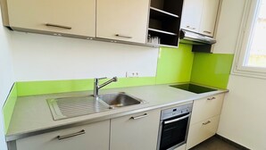Eine Küche mit weißen Schränken, einer Edelstahl-Spüle und einem eingebauten Backofen.