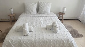 Ein ordentlich bezogenes Bett mit weißer Decke und Kissen, zwei Nachttische mit Lampen und ein flauschiger Teppich auf dem Boden.