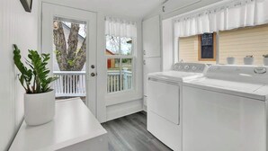 A compact laundry room with a washing machine, a drying rack, and a potted plant. - Awesome Haus With Gameroom, 4blks to Center of Town! (Fredericksburg)