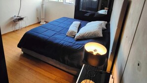 A modern bedroom with a large bed, a flat-screen TV mounted on the wall, a bedside table with a lamp, and a window providing natural light. - Lovely Condo Best City Location. (Mexico City)