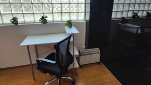 A room with a wooden floor, a white desk with a black office chair, a radiator, and a window with frosted glass panels. - Lovely Condo Best City Location. (Mexico City)