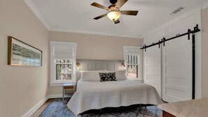 A bedroom with a bed, a ceiling fan, a window, and a sliding door.