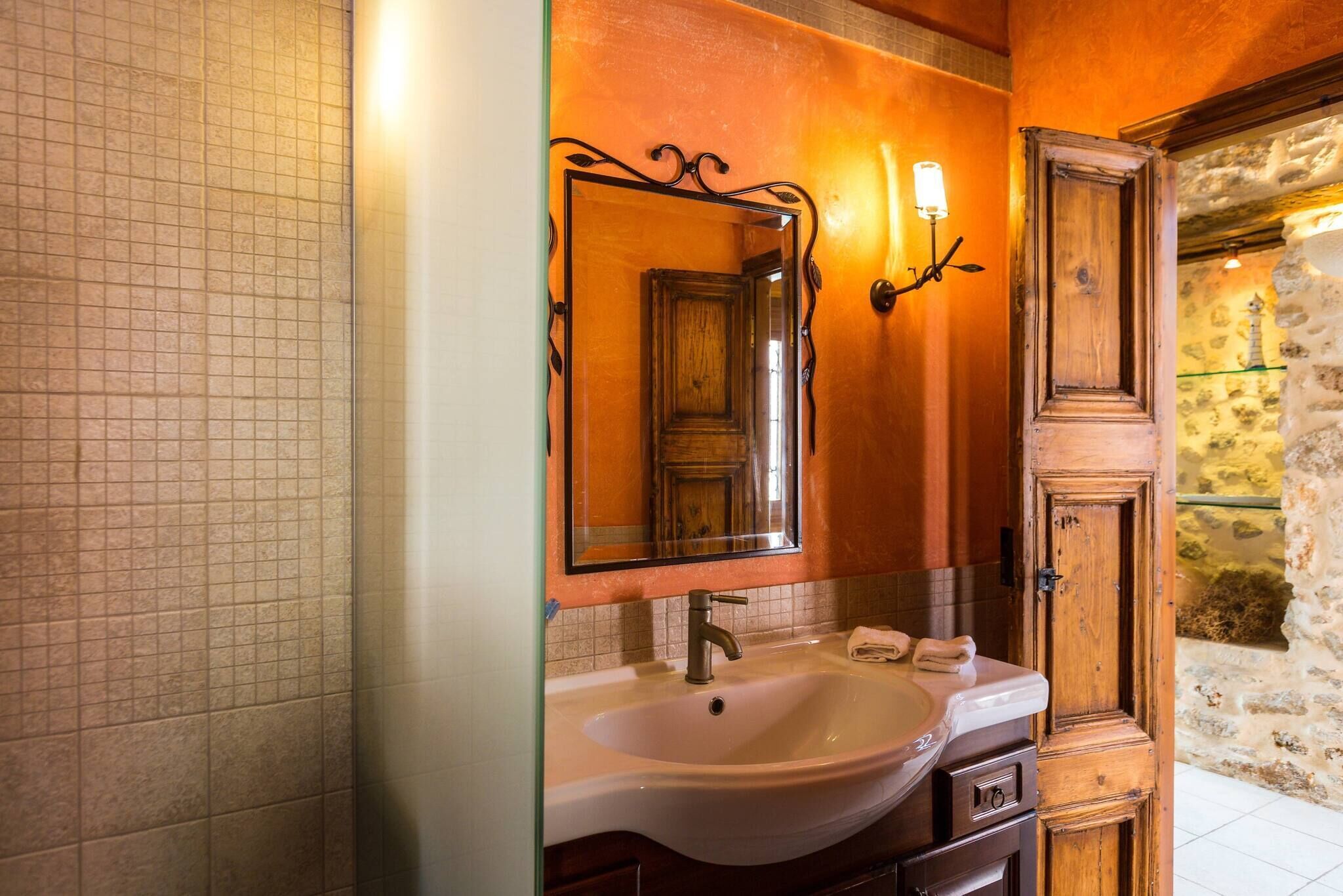 Un bany amb un mirall gran, un lavabo i un armari de fusta.