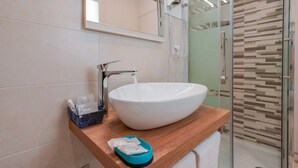 A modern bathroom with a large white sink, a glass shower enclosure, and a wooden vanity. - Bardilio Luxury Rooms IUN P1813 (Cagliari)