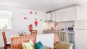 A compact living space with a kitchenette, a dining area, and a sofa with a blanket.
