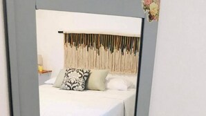 A bedroom with a bed, a bedside table, and a mirror.