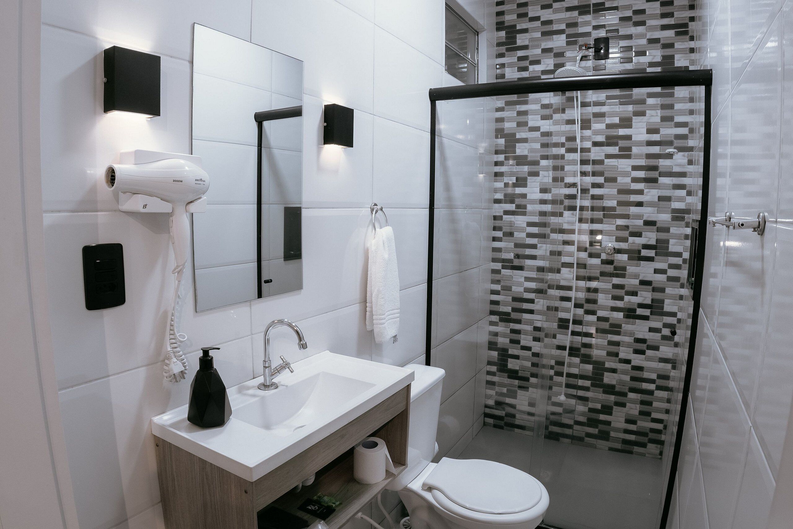Ein modernes Badezimmer mit Waschbecken, Spiegel und Toilette in Weiß.