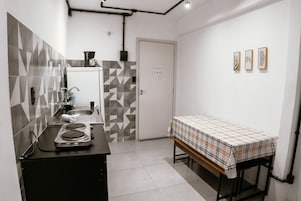 Cozinha compacta com pia, fogão e uma mesa com toalha.