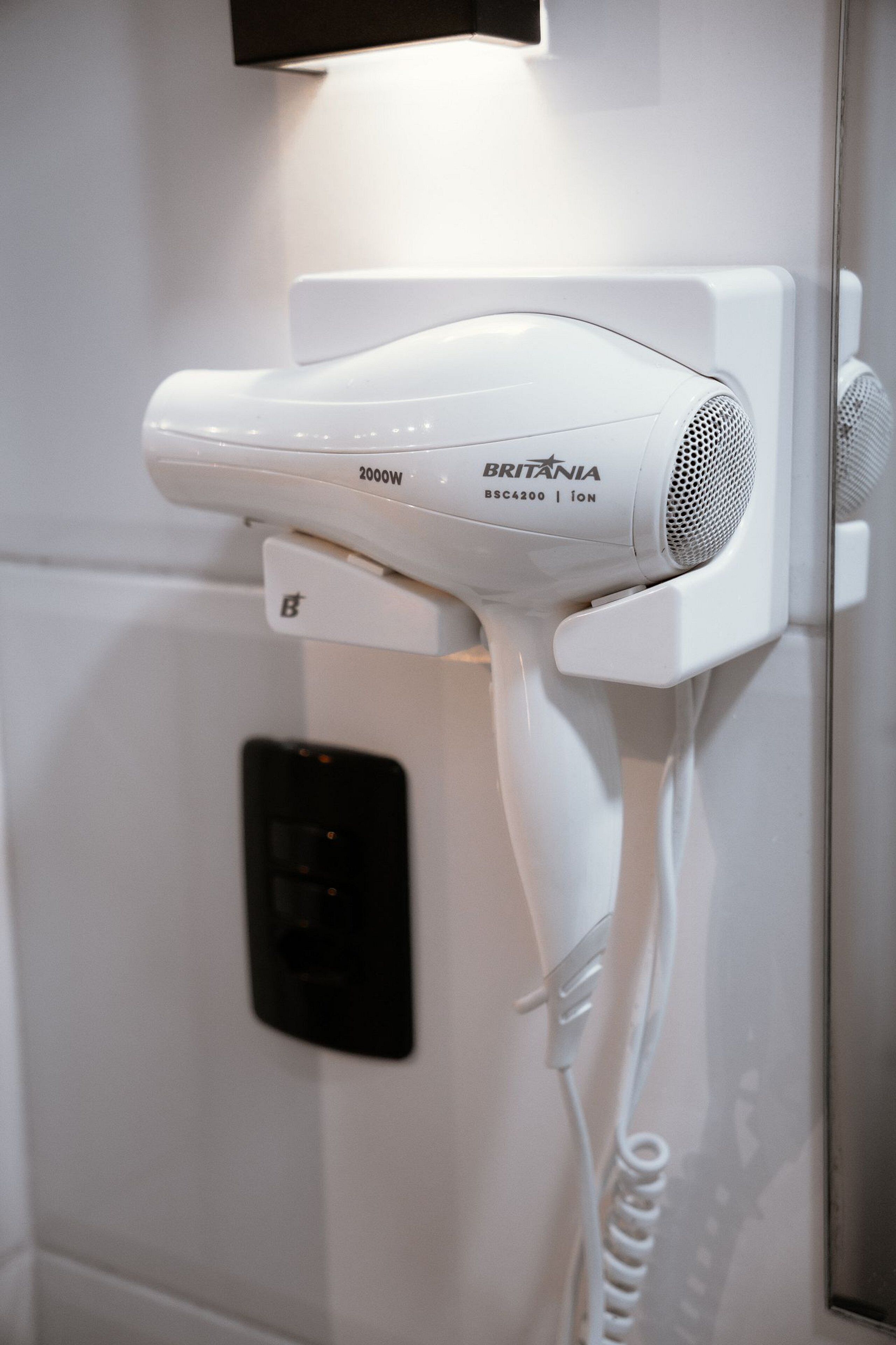 A white hair dryer mounted on a wall with a control panel below it.