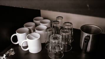 Une collection de tasses blanches et de verres transparents posée sur une surface sombre.