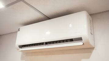 A white air conditioner mounted on a ceiling with a visible brand logo and model number.