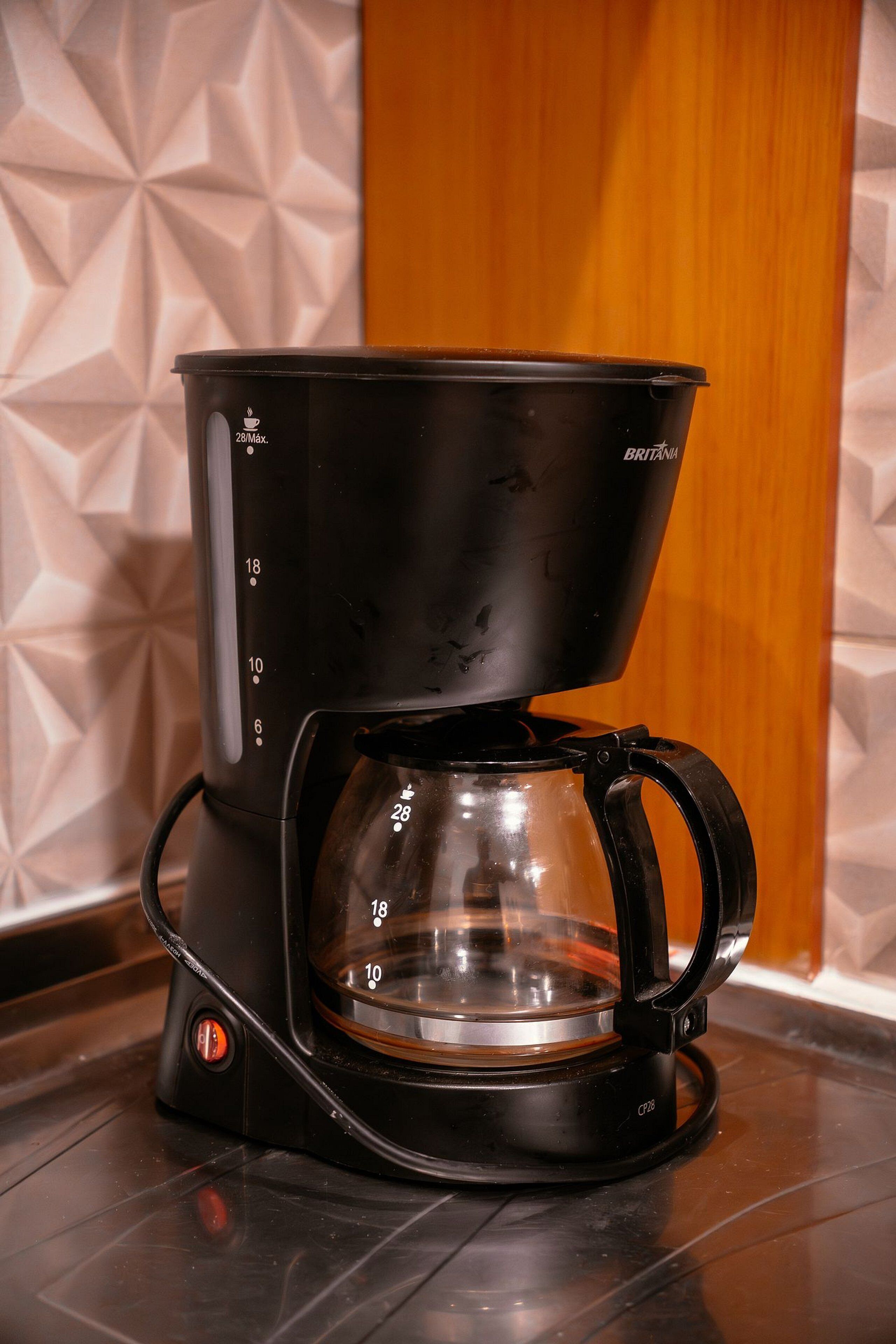 A black coffee maker with a glass carafe and a drip tray on a countertop.