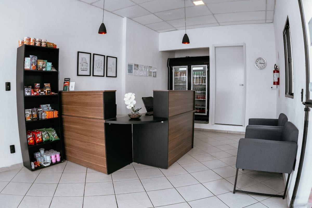 A reception area with a counter, a wooden panel, a refrigerator, and a seating area.