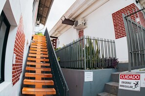 A staircase leading to a building with a metal fence and a sign indicating irregular stairs. - VILLA BILAC 04 (Blumenau)