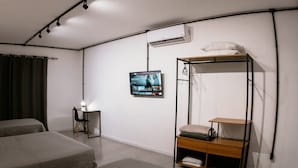 Een kamer met twee bedden, een bureau met stoel, een aan de muur bevestigde televisie en een stapelbed met opbergruimte.