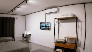 Habitación con dos camas, un escritorio con silla, televisor montado en la pared y una litera con espacio de almacenamiento.