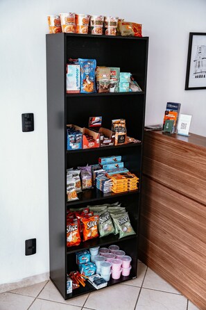 A self-service snack kiosk with various packaged snacks and beverages. - VILLA BILAC 04 (Blumenau)