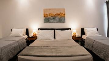 Habitación doble con dos camas, una mesita de noche con lámpara y un cuadro en la pared.