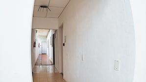 Een gang met een betegelde vloer, witte wanden en een plafond met een lamp.
