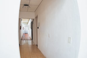 Un pasillo con piso de baldosas, paredes blancas y un artefacto de iluminación en el techo.