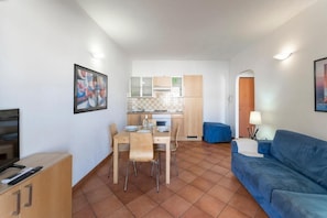 Ett kompakt bostadsutrymme med en matplats, ett litet kök och en soffa.