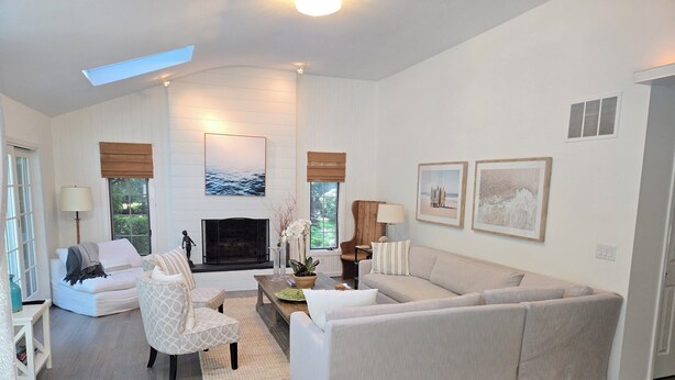 Uma sala de estar moderna com lareira, sofá, poltrona e mesa de centro.