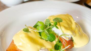 Un plato de huevos Benedict con salmón ahumado y salsa holandesa, adornado con brotes micro.
